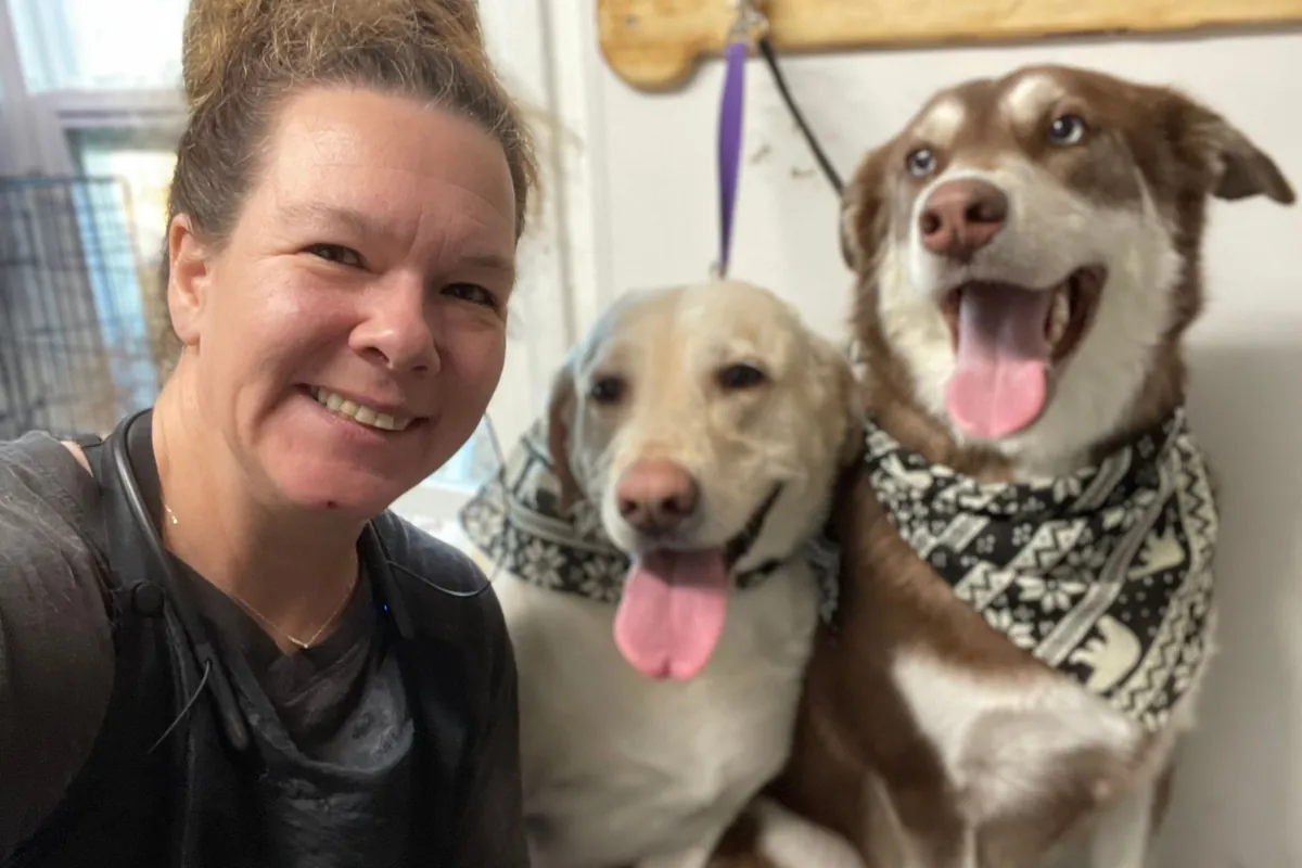 Shanti with two happy dogs wearing bandanas at the grooming station